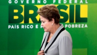 Dilma de costado con colores brasileros detras