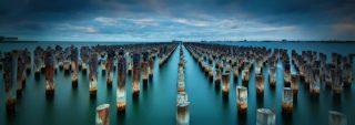 Old Pier Stumps in the blue sea water of Port Melbourne, Australia